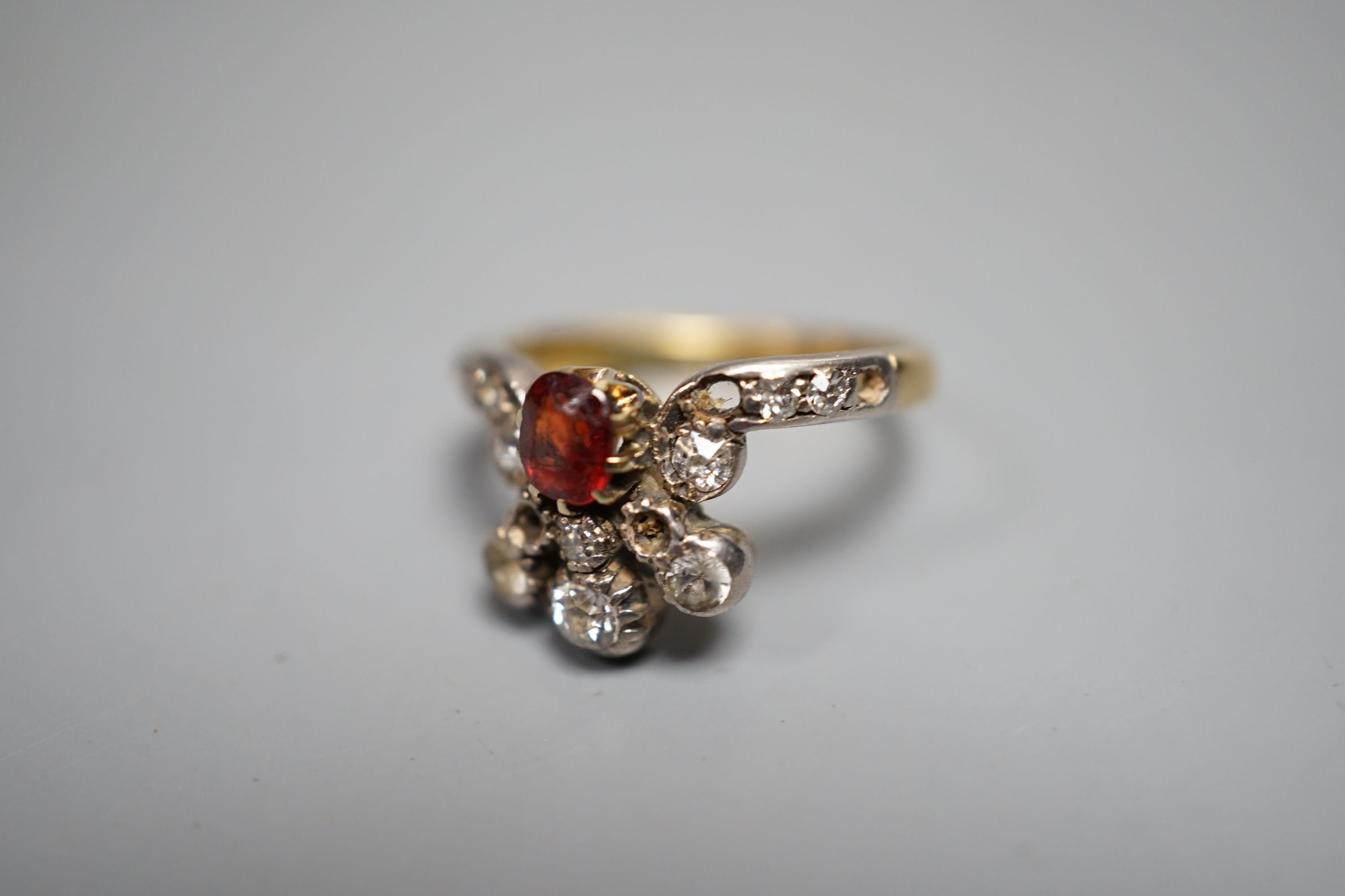 An early 20th century 18ct, garnet? and diamond cluster set dress ring(a.f.), with diamond set shoulders, size J. gross weight 3.5 grams.
